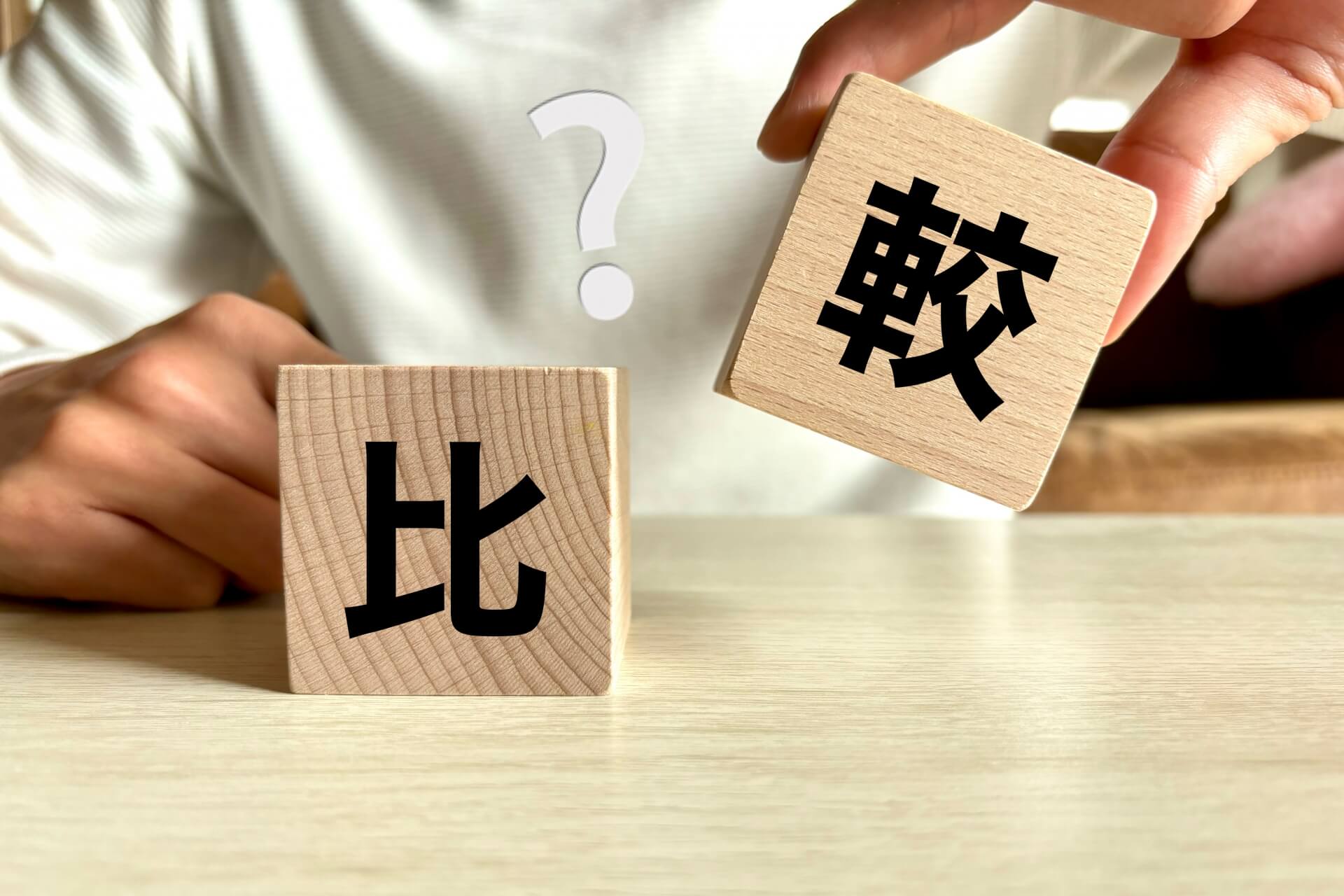 木製ブロックに「比」と「較」の文字が書かれ、比較をイメージした写真。スポーツデポとスポーツアルペンの違いを説明する記事のアイキャッチ画像。