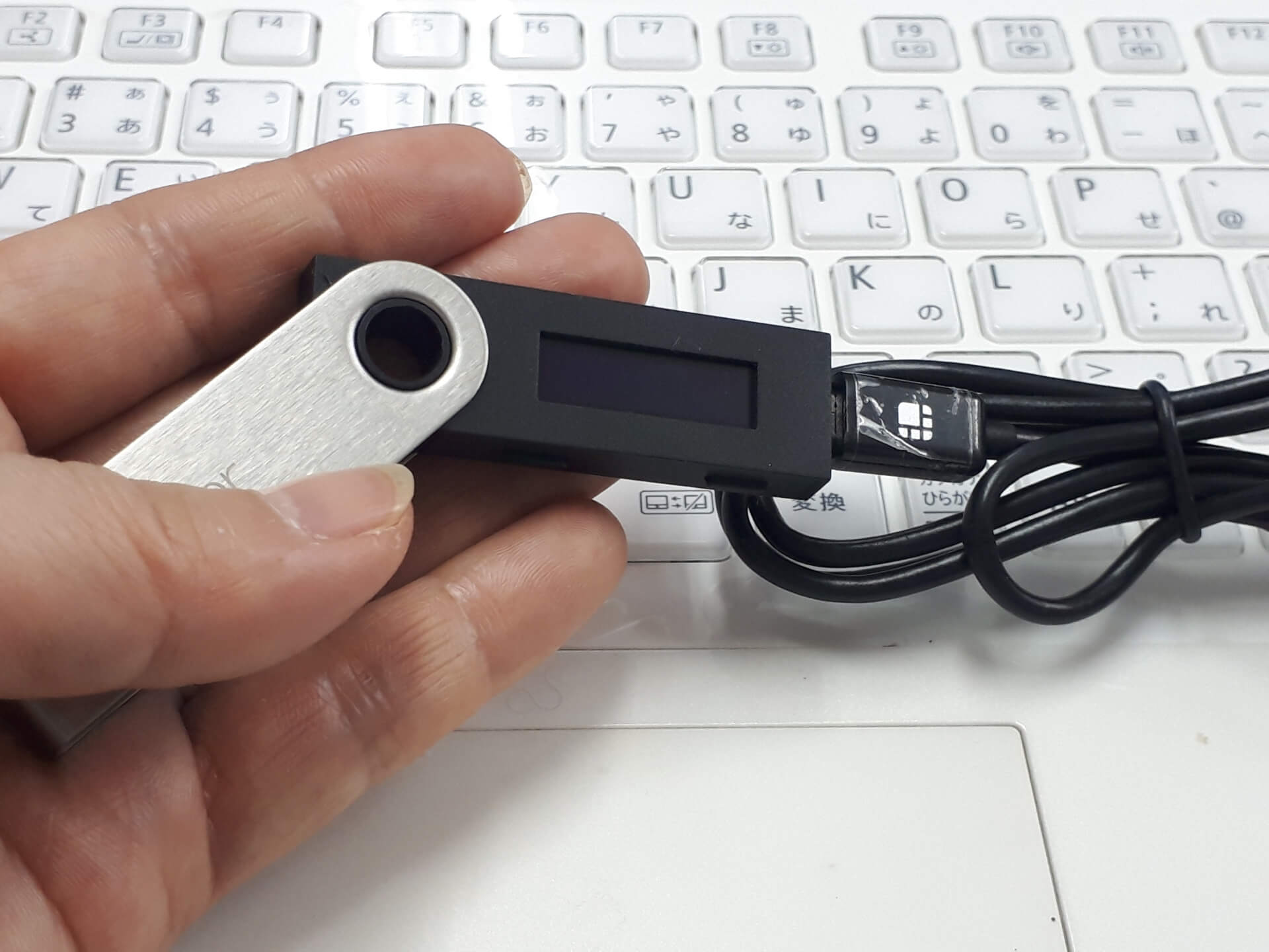 仮想通貨を安全に保管するためのハードウェアウォレットを手に持っている様子