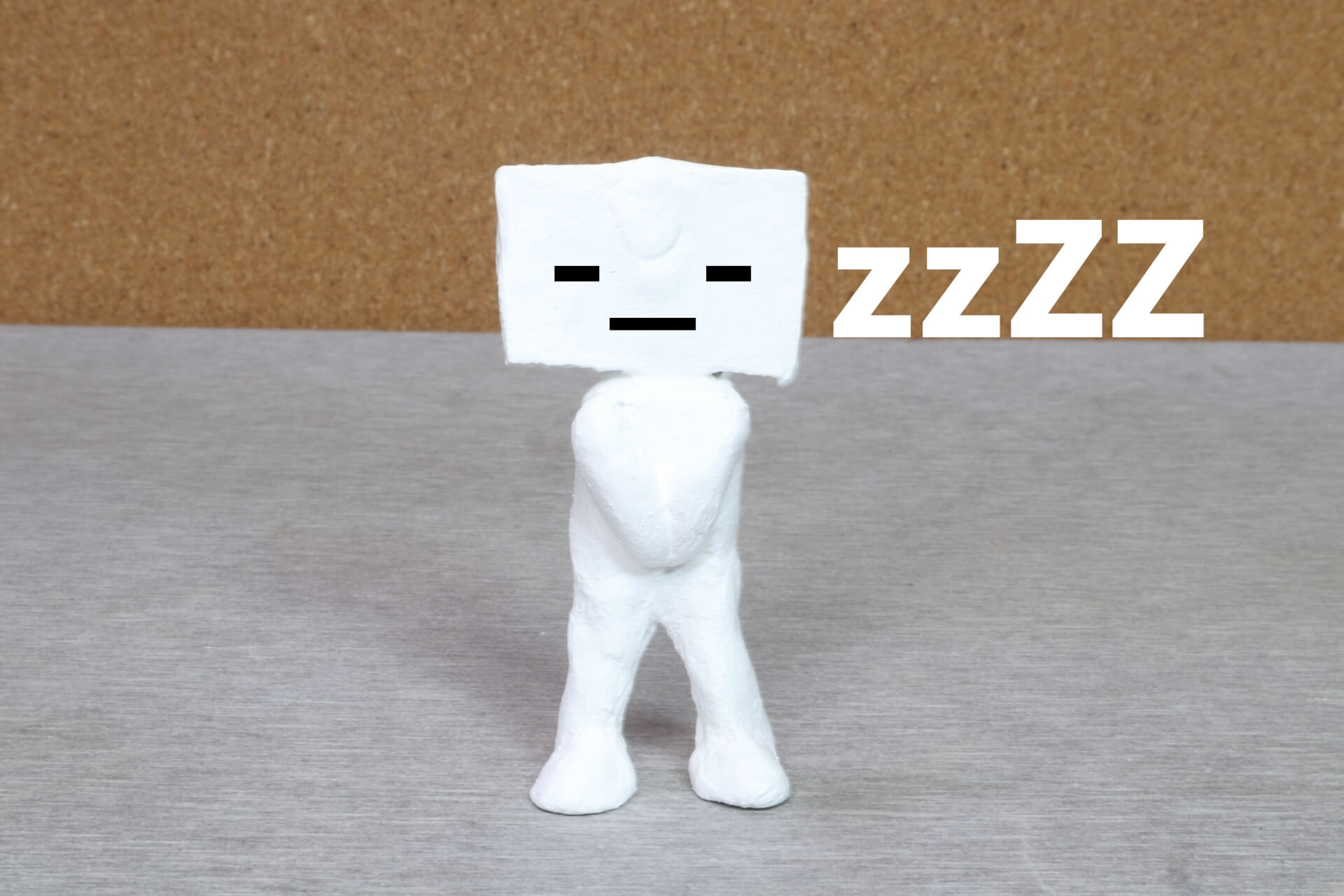 スマートフォンを持つ人形の上に「ZZZZ」と書かれたテキスト