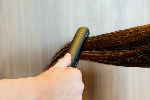 ストレートアイロンで髪を伸ばす様子