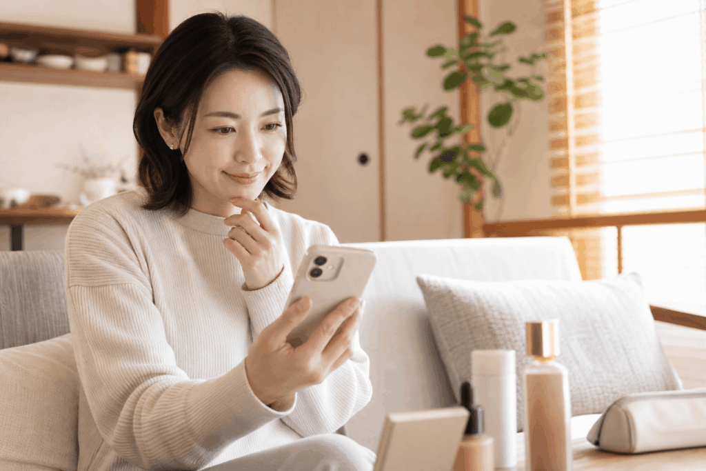 スマートフォンでECサイトを見て化粧品を選んでいる女性