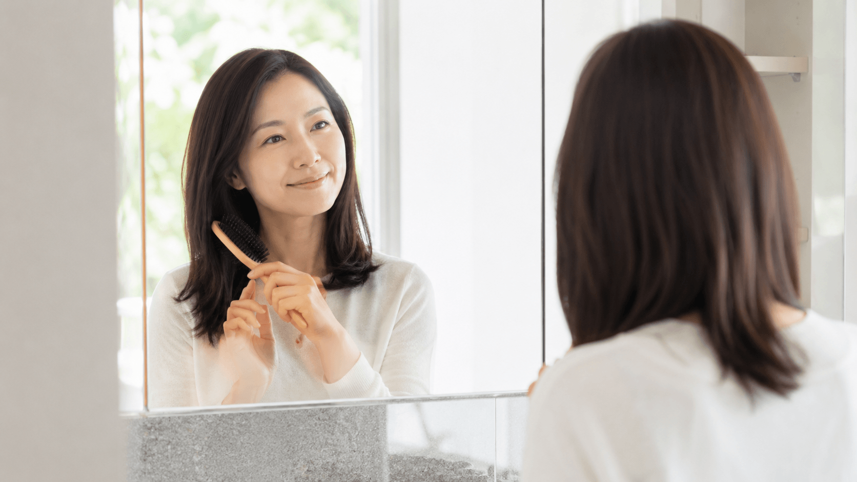 ヘアブラシ 朝晩 使い分け 鏡の前でヘアブラシを手にする女性