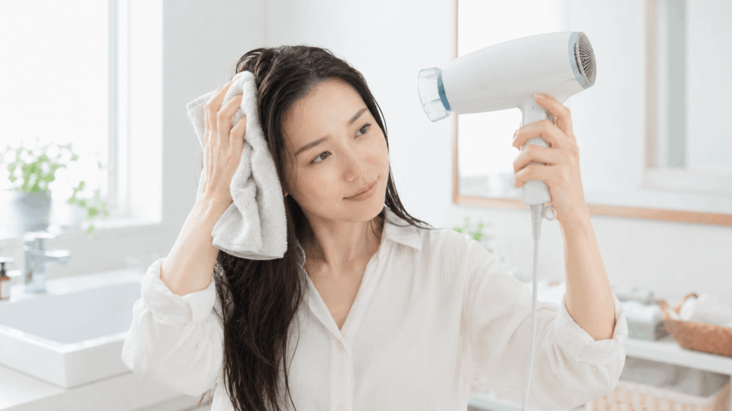 髪の根元をタオルドライしてからドライヤーで乾かす女性の様子