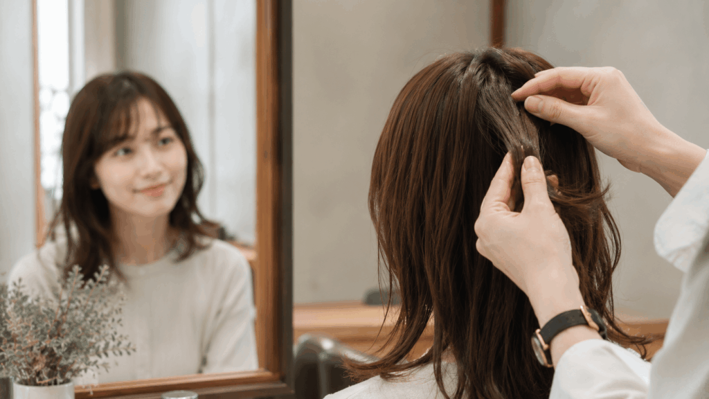 縮毛矯正の周期を考える女性が髪をチェックしているサロンでのシーン
