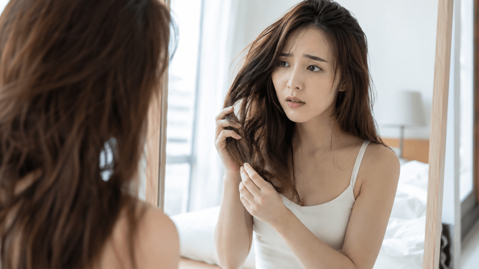 朝起きて髪のまとまりの悪さに気づく30代女性の寝室シーン