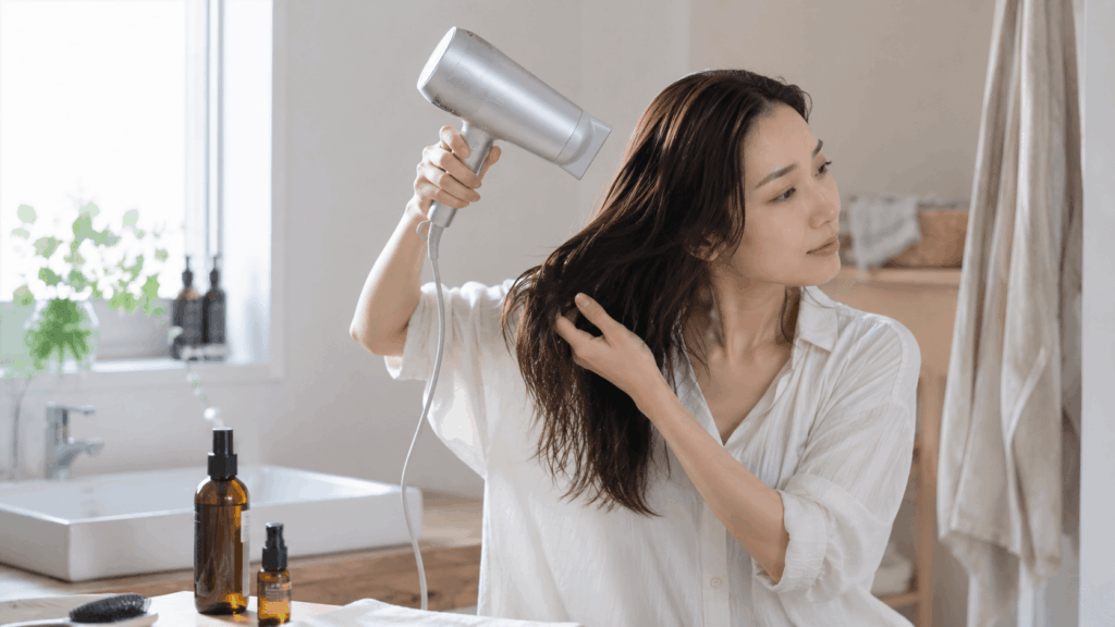 寝る前のヘアケアでドライヤーとトリートメントを使う女性の様子