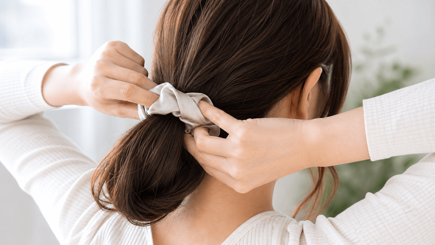 ヘアゴムの跡がつかない結び方を試す女性の手元