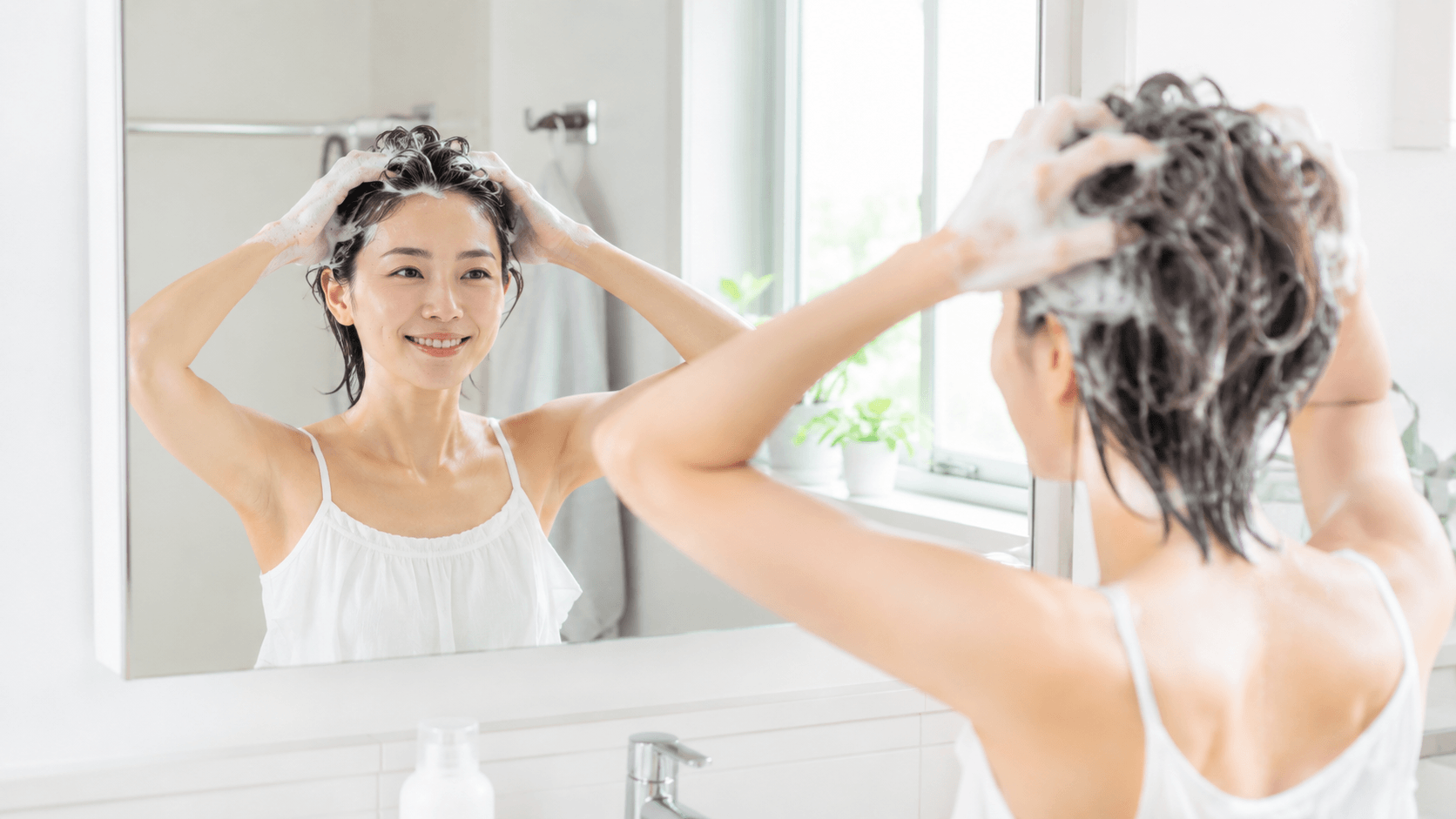 シャンプーを二度洗いする30代女性の自宅バスルームでのヘアケアシーン