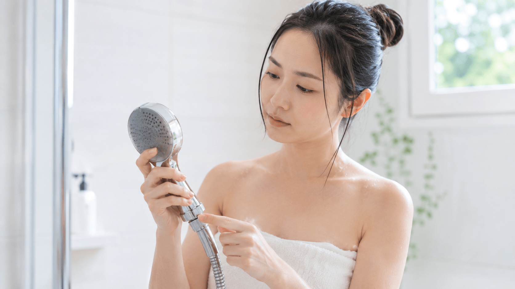 お風呂でシャワーの温度設定を確認する30代女性のシーン