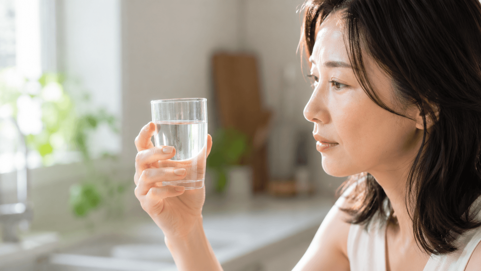 グラスに注がれた水と水分補給を意識する女性のイメージ